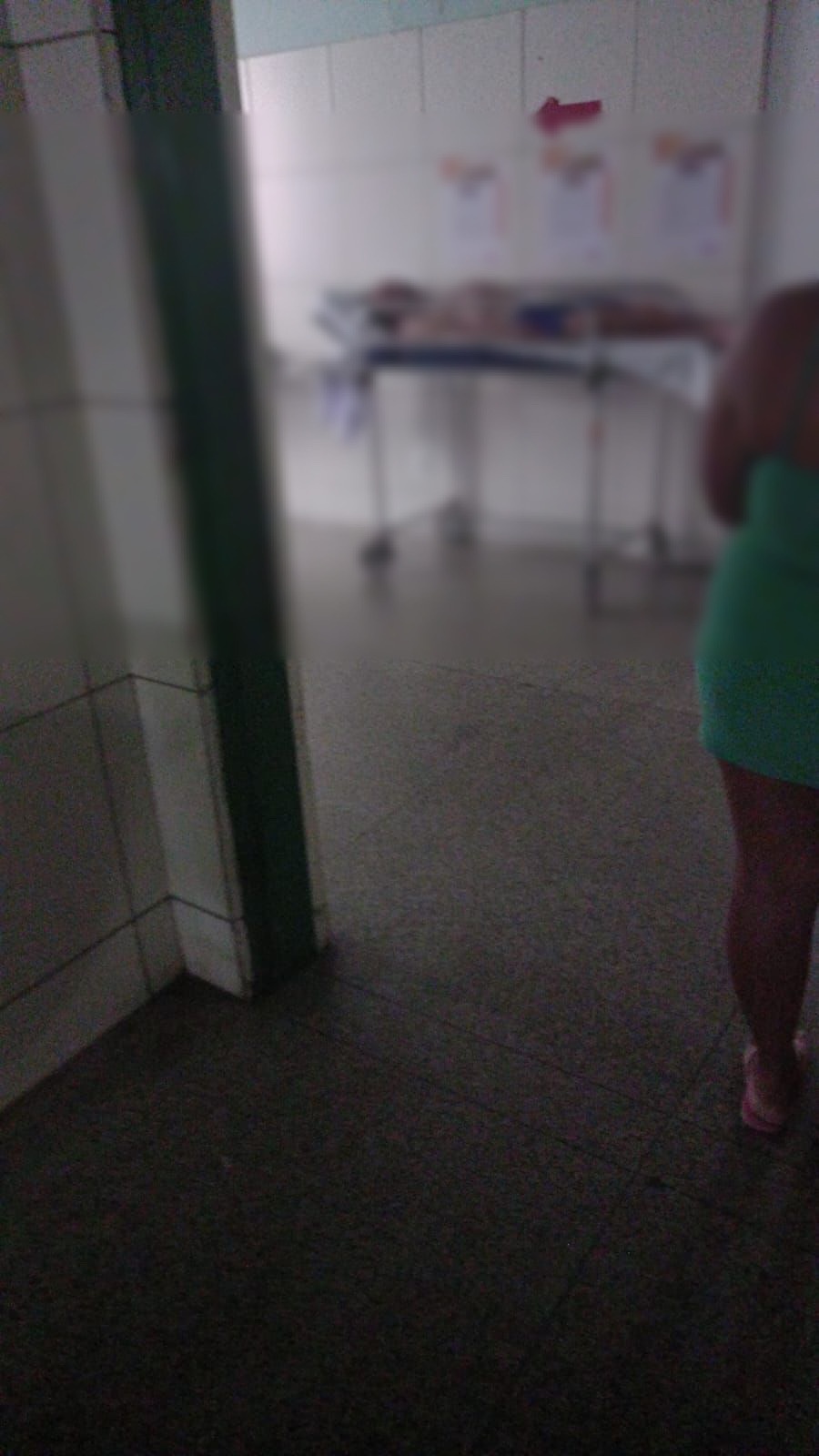 Deitado, só de calção azul, parte do uniforme da prisão, Correia Lima está numa maca no HUT
