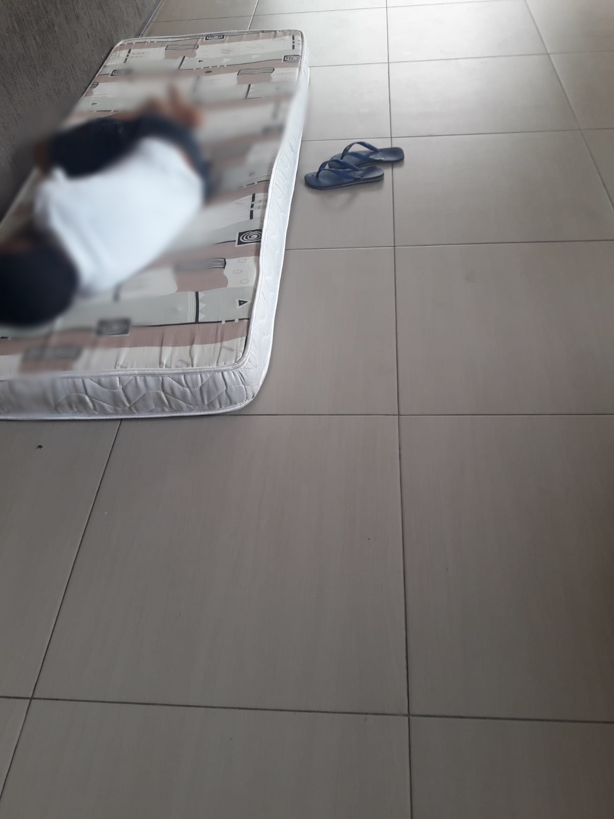 Criança dorme em colchão no chão em abrigo do Estado