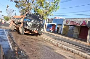O caminhão ficou preso na cratera que se avriu na via (Foto: Reprodução)