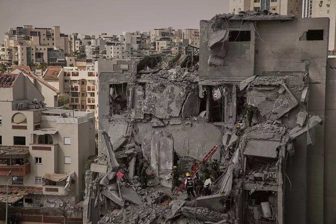 Equipas de salvamento trabalham no meio dos escombros de edifícios residenciais destruídos por um ataque mortal de mísseis iranianos em Beersheba, Israel, terça-feira, 24 de junho de 2025.