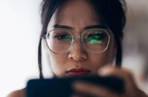 Mulher acompanha oscilação de cotações de investimento no celular (Foto: shih-wei/Getty Images)