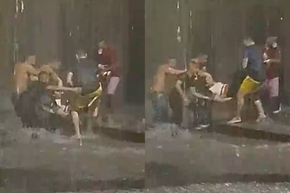 Mulher sendo resgatada por moradores após ser arrastada por correnteza