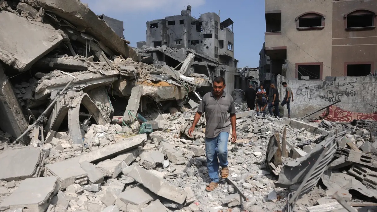 Um palestino caminha ao lado dos escombros de uma casa atingida por ataques israelenses em Jabalia, no norte da Faixa de Gaza. 30/06/2025