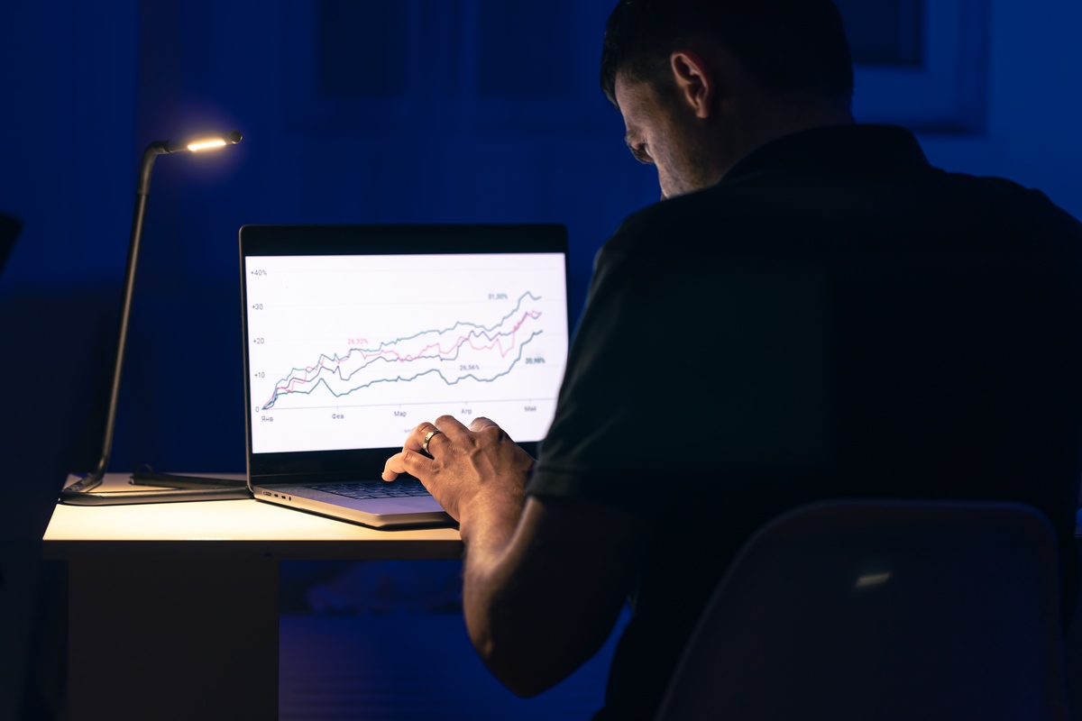 Homem negociando browsing online investimentos de ações à noite