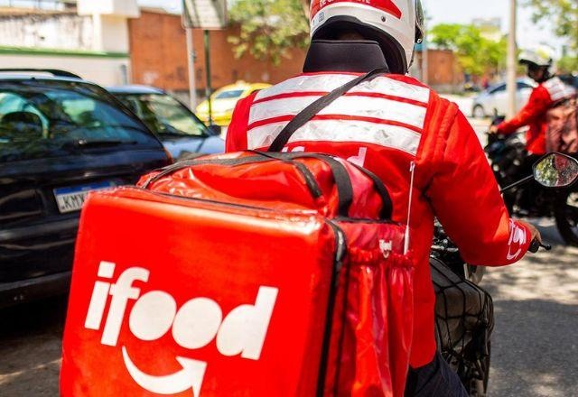 Entregador circula com mochila do iFood durante serviço de entrega.
