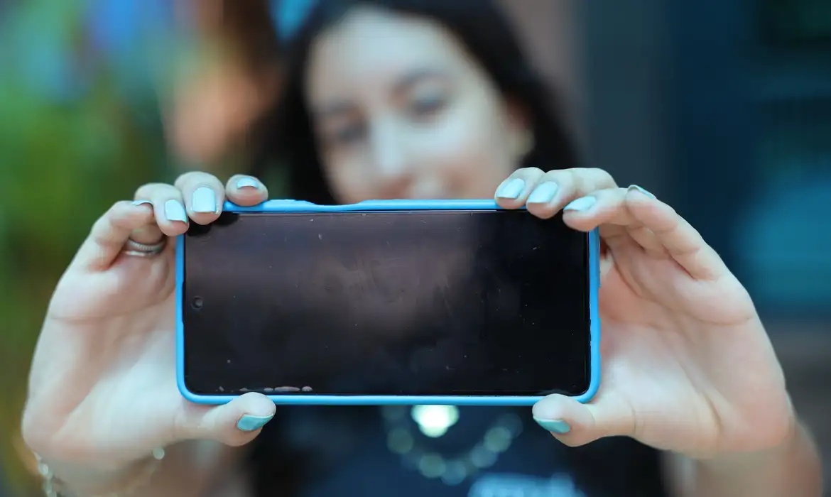 Estudante usa celular em escola; uso de dispositivos digitais é analisado pelo Pisa 2025.