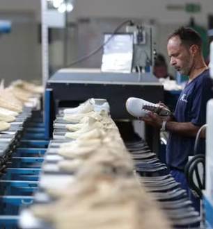 Funcionário trabalha em linha de produção de fábrica de calçados no Brasil.